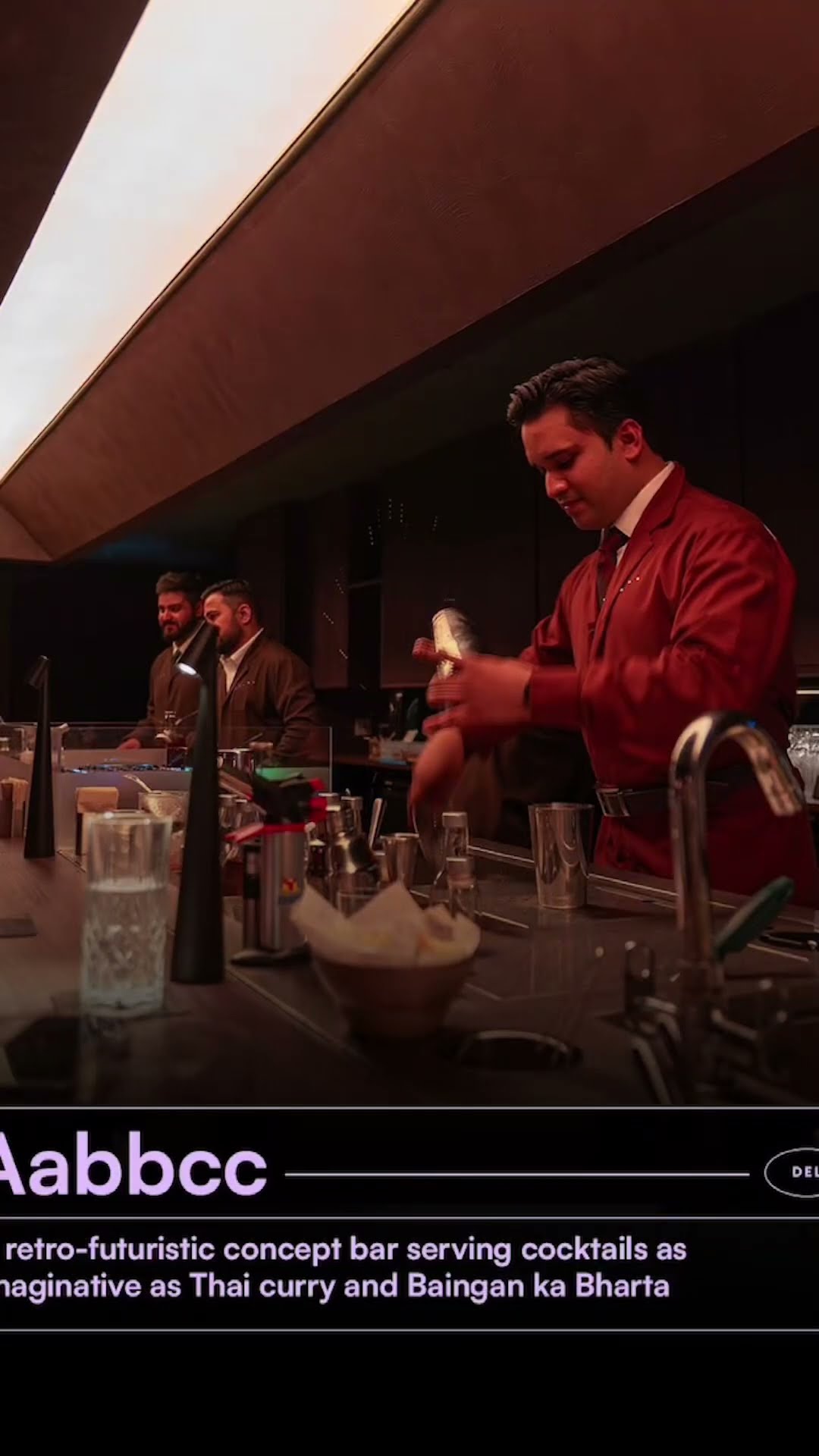 A server in a red jacket at Aabbcc, described as a retro-futuristic concept bar