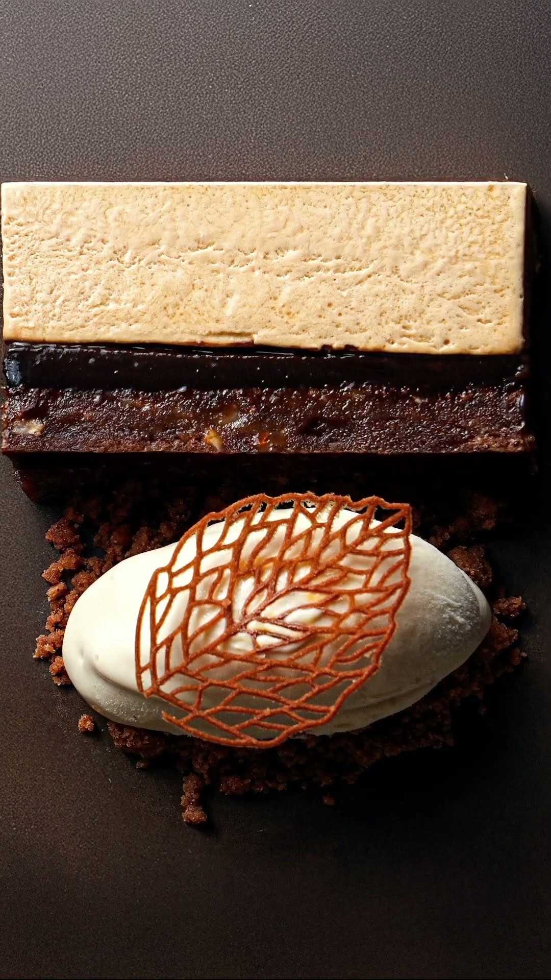 A plated layered dessert with a quenelle and a decorative tuile