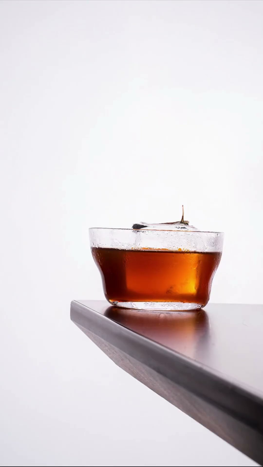A single amber cocktail on a grey ledge against a pale wall