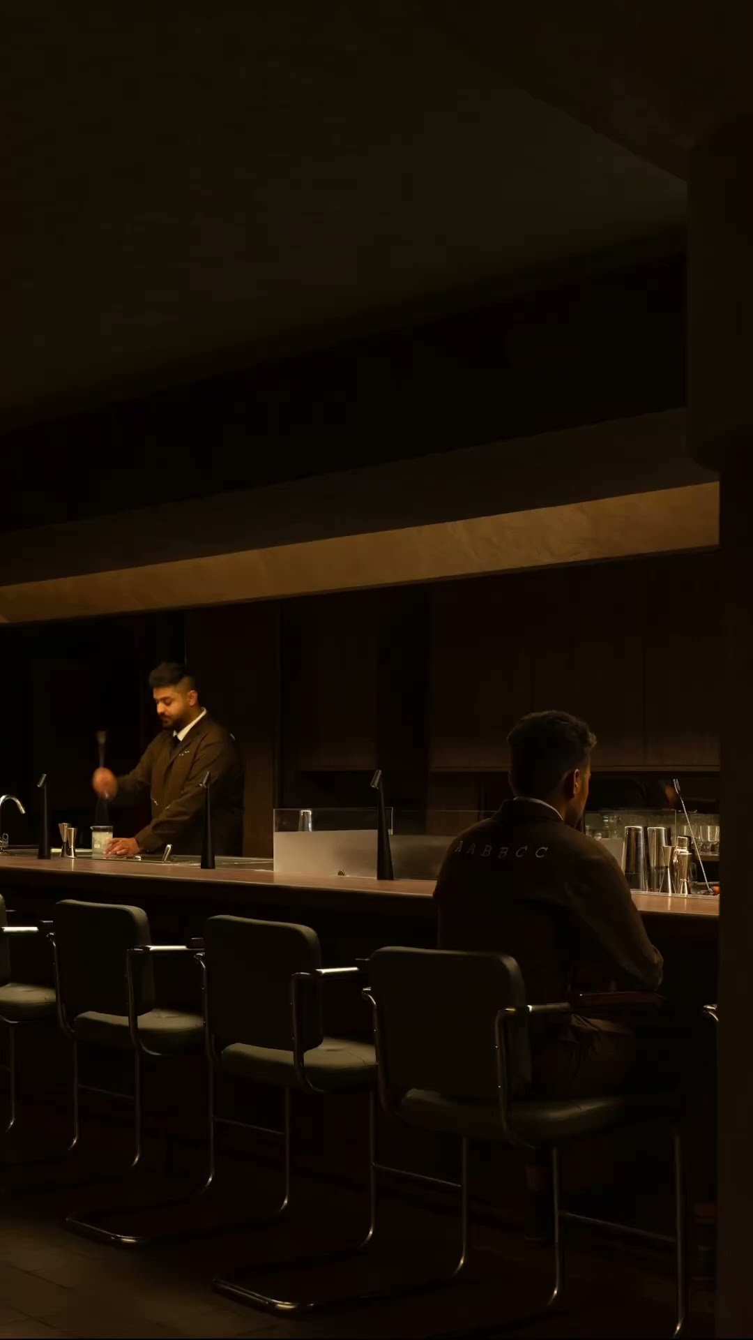 Two guests at the far end of a dark bar room