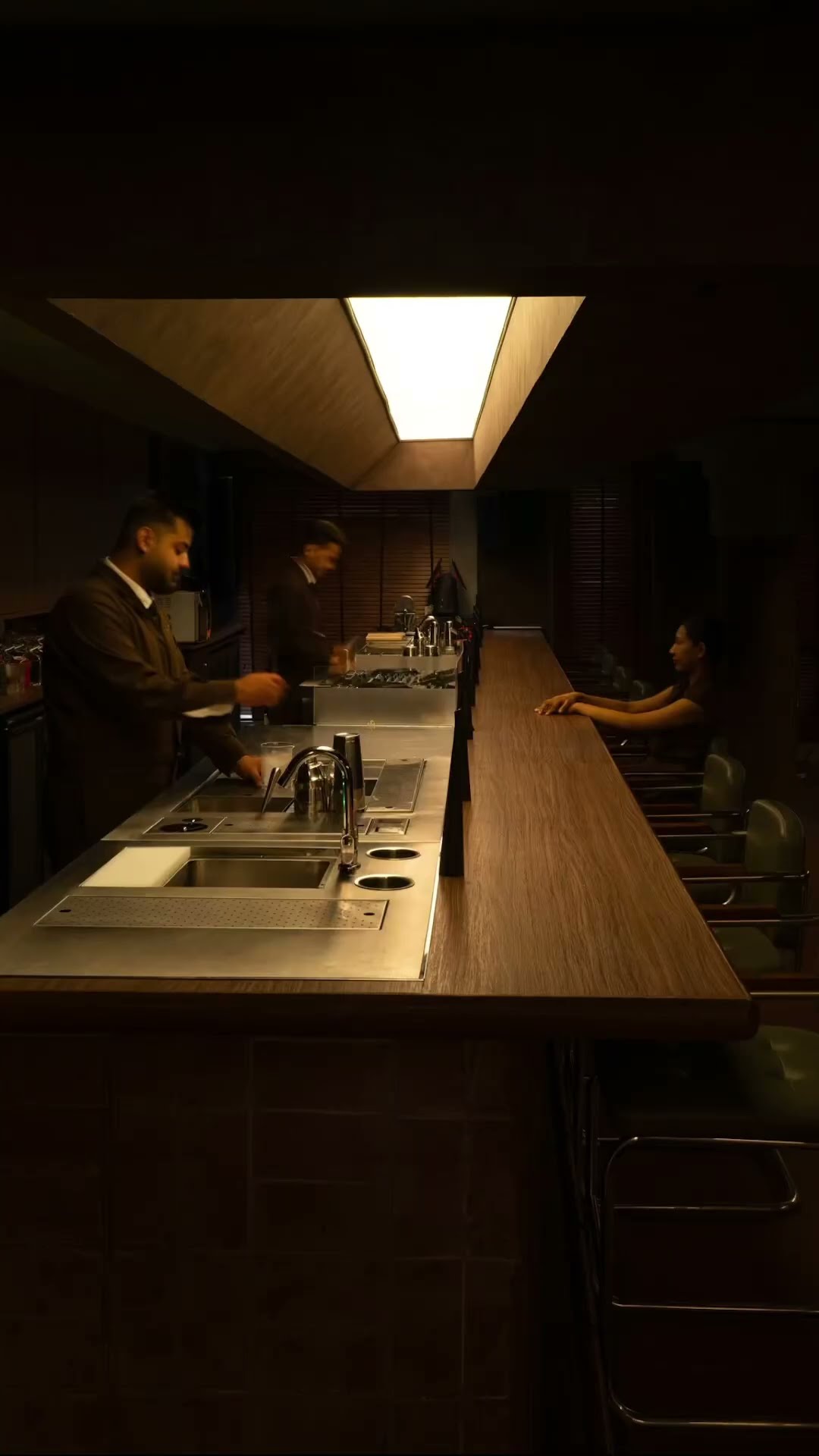 Bartenders working behind a long lit bar counter