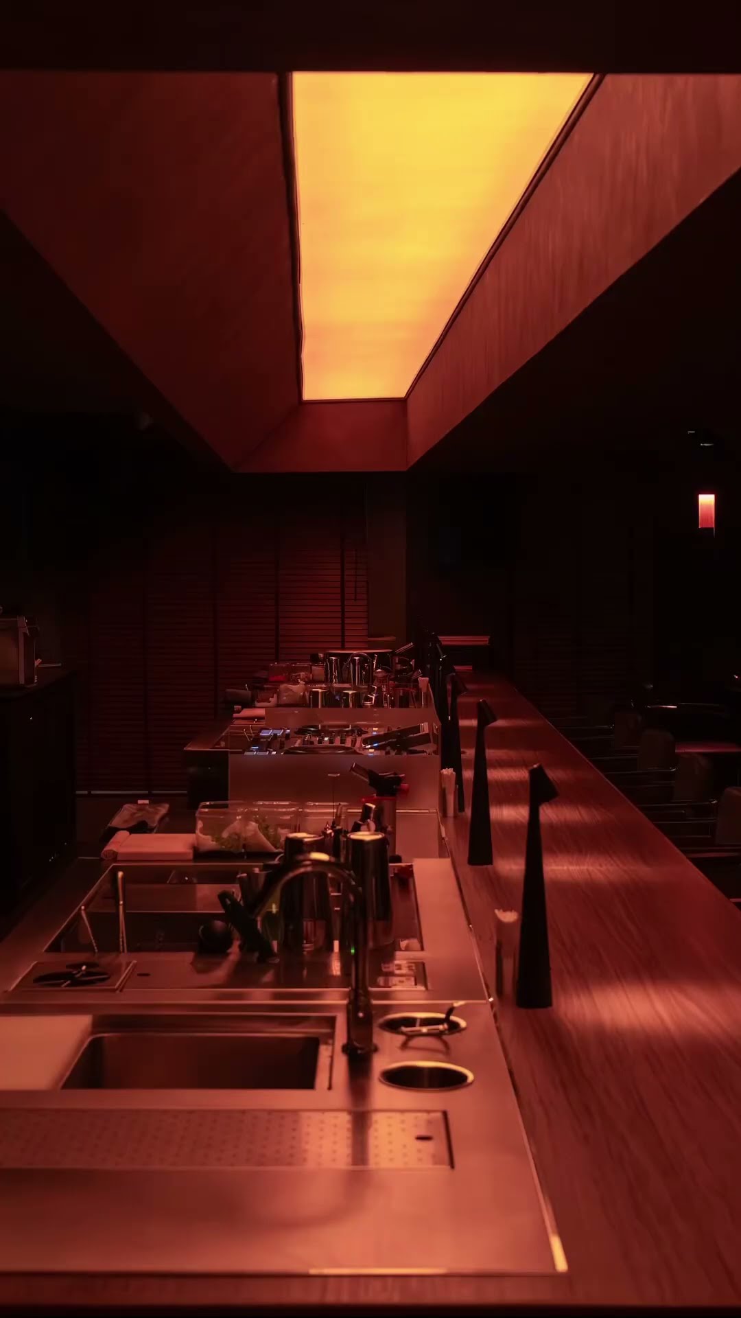 A long bar counter running beneath a warm orange ceiling light