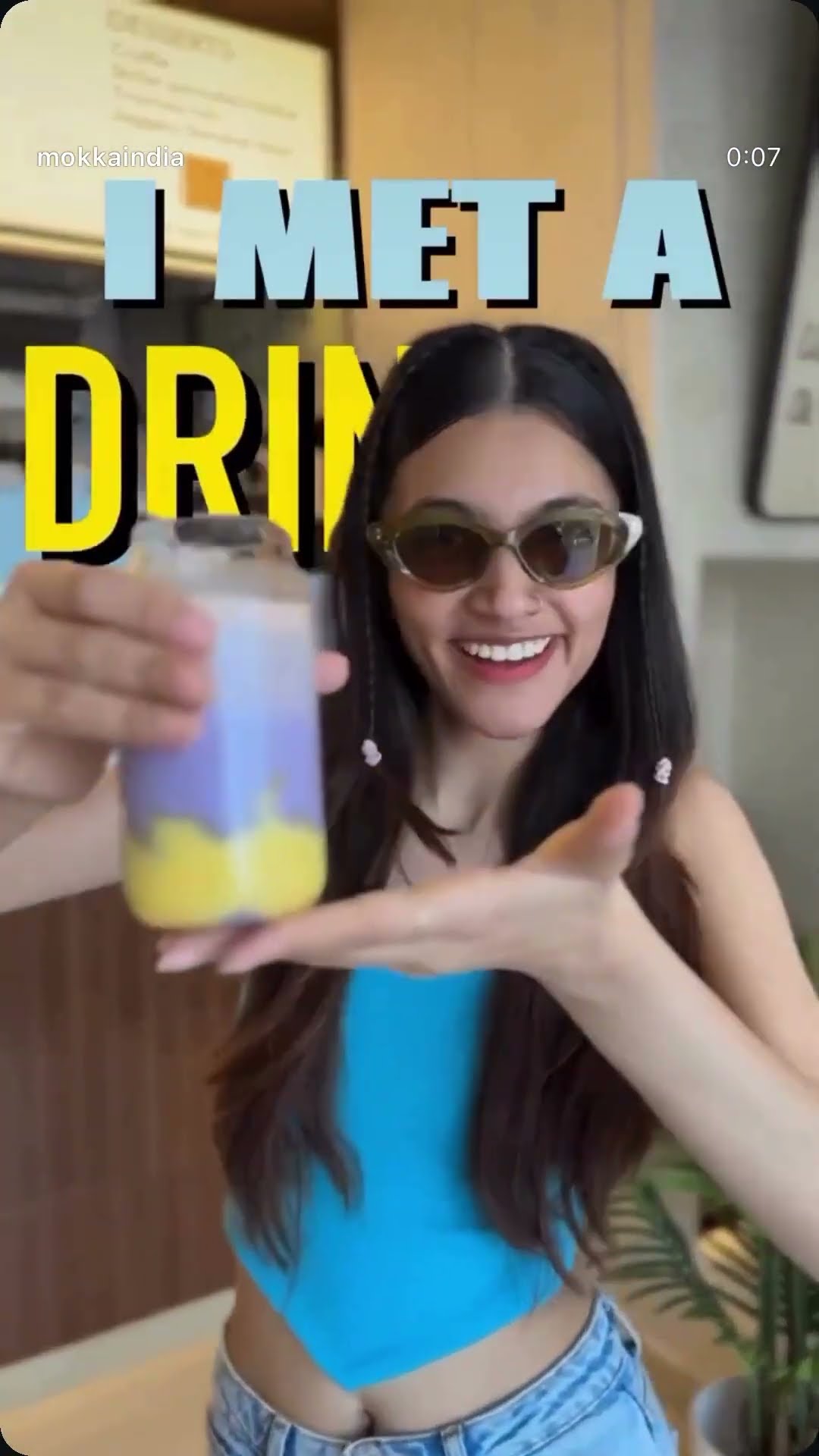 A creator in sunglasses presenting a layered iced drink