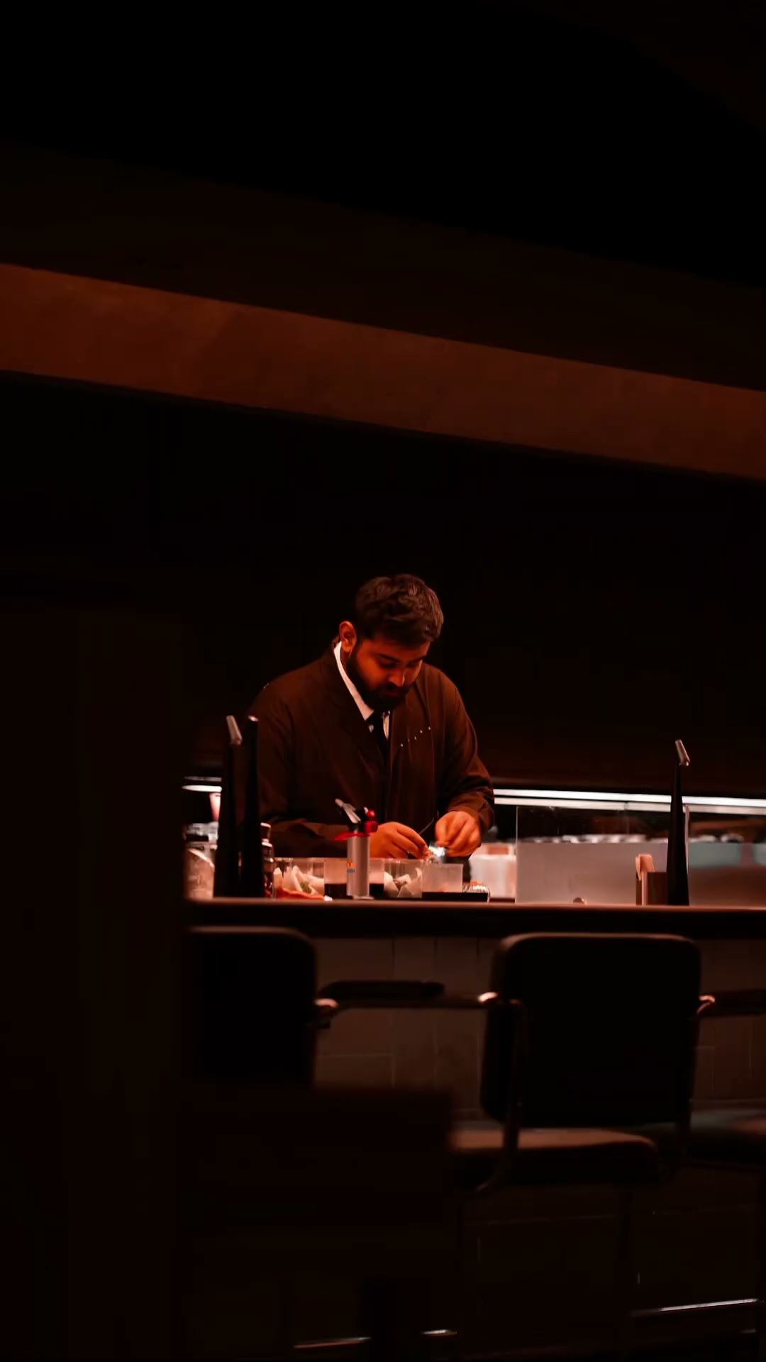 A bartender preparing a drink at a darkened bar