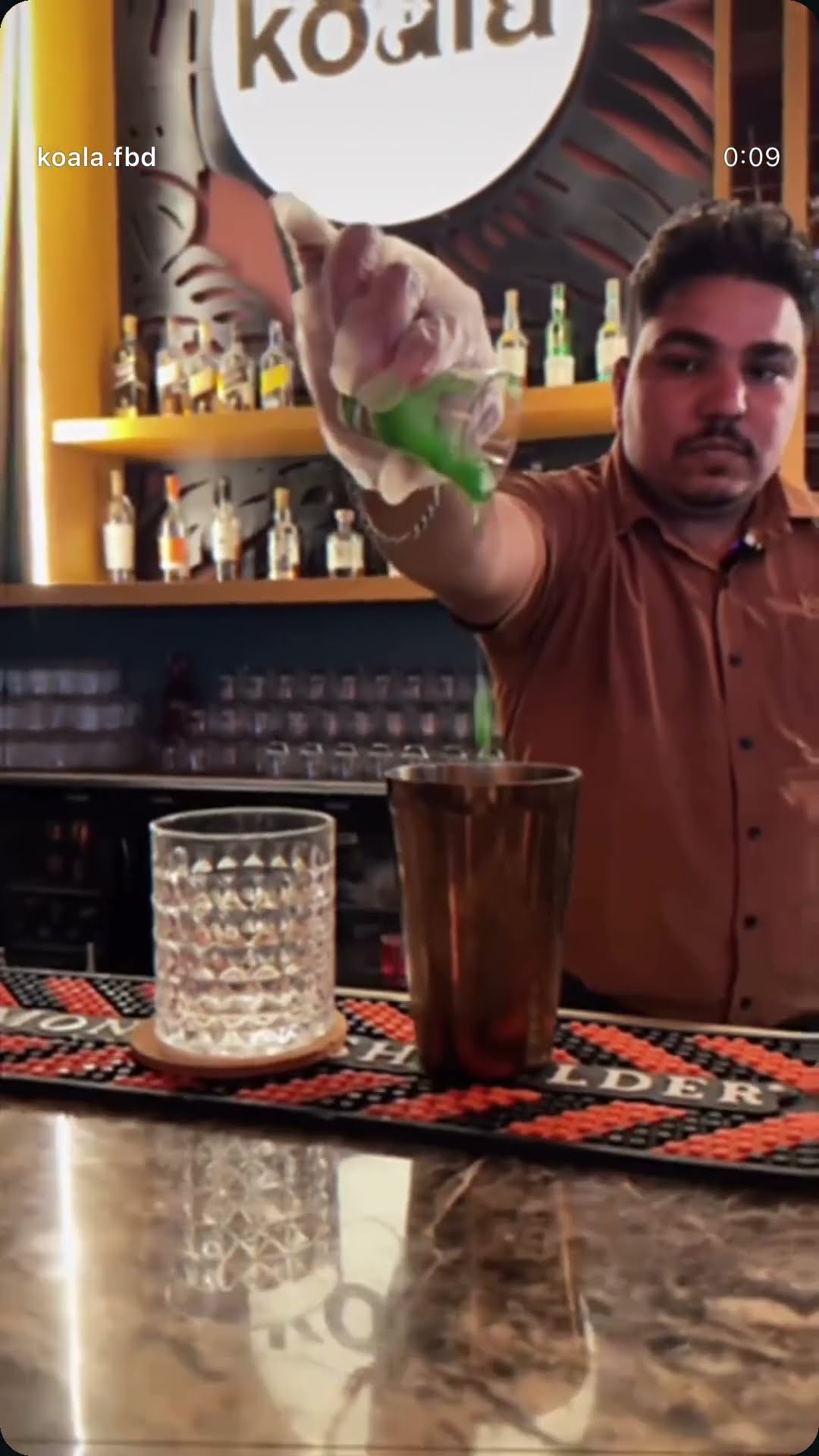 A bartender pouring a cocktail across the bar at Koala